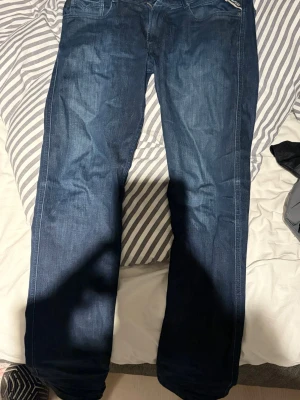 Mörkblå jeans från Replay - Storlek: W31 L32 Snygga mörkblå jeans från Replay med klassisk femficksdesign och raka ben. Jeansen har en diskret tvättad look och är tillverkade i denim. Perfekta för dig som gillar en stilren och tidlös look.