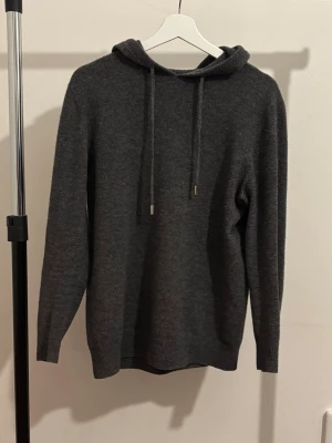 Mörkgrå hoodie i kashmir - Mörlgrå  hoodie med i kashmir med okänt märke. Den är oanvänd och är i mycket bra/nytt skick.