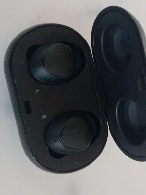 Samsung svarta trådlösa in-ear hörlurar - Säljer ett par svarta trådlösa in-ear hörlurar från Samsung. De kommer i ett smidigt, ovalt laddningsetui i plast med Samsung-logga på locket. Hörlurarna har en minimalistisk design och sitter bekvämt i öronen. Perfekta för musik, poddar och samtal.
