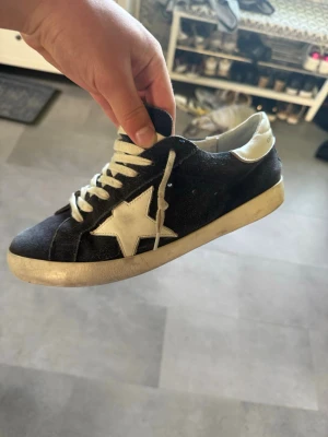 Svarta sneakers med vit stjärna - Ett par feta Golden goose i färg navy/white. Storlek 42 men passar 42-43 då dem är rätt mjuka. Skriv vid funderingar:)