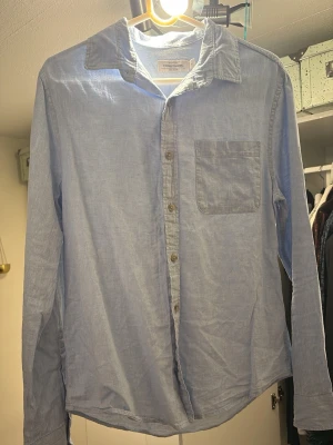 Ljusblå linneskjorta från Dressmann - Klassisk ljusblå skjorta från Dressmann i linne. Skjortan har lång ärm, bröstficka och knappar framtill. Perfekt till jeans eller chinos för en clean och enkel stil. Perfekt till sommaren! Hör av er vid frågor!👍