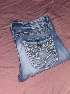 Blå bootcut jeans från Big Star - Snygga blå bootcut jeans från Big Star med dekorativa sömmar på bakfickorna och slitna detaljer framtill. Klassisk femficksmodell med knapp och dragkedja. Perfekta för en avslappnad och trendig look. Köptes på Vinted, perfekt skick men för små för mig:)