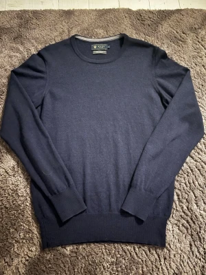 Mörkblå merinoull tröja från Riley - Snygg mörkblå tröja från Riley med rund halsringning och långa ärmar. Tröjan har ribbade muddar vid ärmslut och nederkant, vilket ger en clean och stilren look. Modellen är 176 och väger 62kg. Det är storlek S men passar mer som Xs. Hör av er om ni har några frågor!☺️