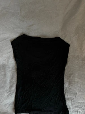 Svart ärmlös topp från 157 - En enkel svart topp från 157 i storlek XS. Toppen är ärmlös och har en rak, klassisk passform som funkar till det mesta. 