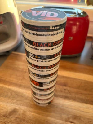 VID Black Orange nikotinpåsar - Säljer flera burkar VID Black Orange nikotinpåsar. Dosorna är vita med svart och orange detaljer och tydlig text. Smaken är Black Orange och burkarna är tillverkade i Sverige. Perfekt för dig som gillar nikotinpåsar med fruktig smak. Förvaras välkyld. Bäst före 2027