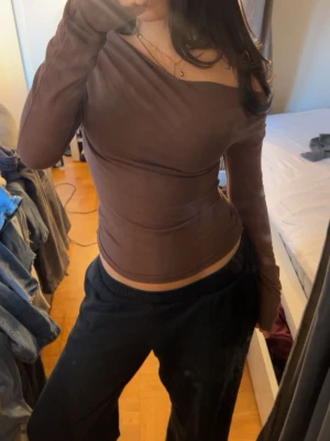 Brun offshoulder topp från Nelly - Säljer en brun långärmad offshoulder topp från Nelly i mjukt stretchigt material. Toppen har en tight passform och sitter snyggt över axlarna. Perfekt för dig som vill ha en enkel men trendig look.