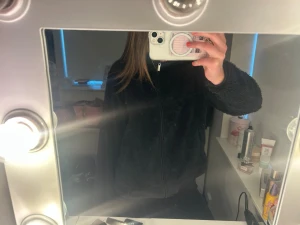 Svart teddyjacka med dragkedja - Mysig svart teddyjacka från 157 med hög krage och dragkedja framtill. Jackan har två sidofickor och är gjord i fluffigt teddy-material som håller dig varm. Perfekt för dig som gillar en avslappnad och trendig stil.