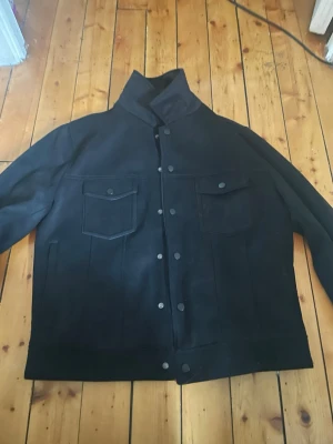 Svart jeansjacka från ZARA - Stilren svart jeansjacka från ZARA med klassisk rak passform. Jackan har två bröstfickor med lock och knappar framtill. Insidan är fodrad för extra komfort och har en diskret ZARA-logga. Perfekt för dig som gillar minimalistisk och modern stil. Jackan är hyfsat tjock o perfekt för höst,vår och tidig sommar, storlek M funkar på S också då armarna går att vika upp