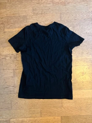 Svart t-shirt från Newbody - En klassisk svart t-shirt från Newbody i 100% bomull. Enkel och stilren design med rund hals och korta ärmar. Perfekt basplagg till garderoben och lätt att matcha med allt.