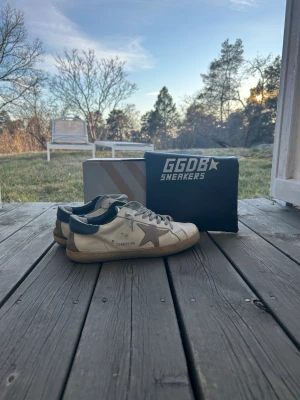 Golden Goose  - SÅLDA!!! Säljer dessa feta Golden Goose i vit färg och beige stjärna! Skicket är ändå rätt så bra, en skada vid högra stortån men inget som märks riktigt. Kan repareras enkelt! Storlek 43, ca 27cm på insidan. Nypris på dessa är 5699kr. Box och dustbag ingår ej! Skriv vid funderingar eller frågor! 🍾💯🙌🏼