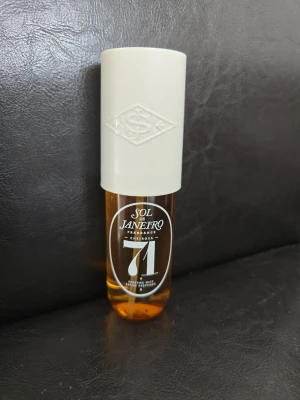 Sol de Janeiro Cheirosa 71 parfym - Sol de Janeiro Cheirosa 71 är en parfym med en elegant, cylinderformad flaska i bärnstensfärgat glas och ett vitt lock med präglad logotyp. Doften är känd för sina varma, söta toner och flaskan har en modern och stilren design.Enbart testad doften.