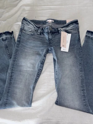 Lågmidjade jeans Gina tricot  - Jättesnygga Lågmidjade blå / ljusblå jeans ifrån Gino Tricot med snygga detaljer på fickorna ! Helt nya med prislappen kvar! Uppsprättade där nere men som sagt aldrig använda och prislapparna sitter kvar!💕💕  Storlek M Young 14+