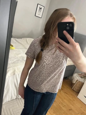 Vit/röd mönstrad t-shirt - Säljer en vit/mörkröd t-shirt med fint känt mönster. T-shirten har korta ärmar och en avslappnad passform. Perfekt till jeans eller kjol för en chill look. Materialet känns mjukt och skönt mot huden. Säljer också jeansen! 