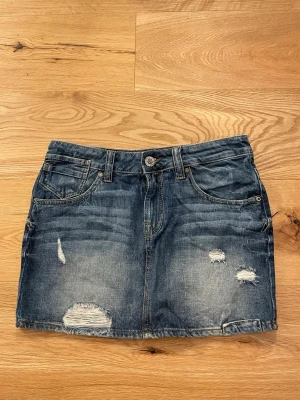 Blå jeanskjol från only!! 🥰🥰💞 - Snygg blå jeanskjol från ONLY med slitna detaljer och klassisk femficksdesign. Kjolen har bälteshällor, knapp och dragkedja framtill samt råa kanter för en trendig look. Perfekt för dig som gillar en avslappnad och cool stil.