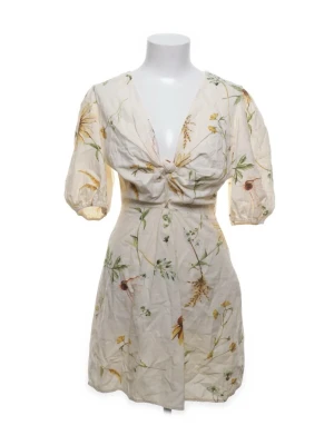 Blommig kortklänning med puffärm - Supersöt kortklänning i ljusbeige med blommigt mönster och puffärmar. Klänningen har v-ringning, knyt i ryggen och voluminösa ärmar som ger en romantisk vibe. Köpt secondhand men har aldrig använt själv då den är för liten tyvärr. Klänningen är ihopsydd där framme❣️