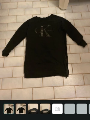 Svart sweatshirt från Calvin Klein Jeans - Svart långärmad sweatshirt från Calvin Klein Jeans med stort CK-logotyptryck på bröstet. Tröjan har rund halsringning, ribbade muddar och dragkedjedetalj i sidan. Tillverkad i mjukt material som känns skönt mot huden.