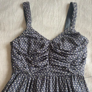 Mörkblå prickig klänning - Supersöt mörkblå klänning med vita prickar och breda axelband. Klänningen har rynkade detaljer över bysten och en dragkedja i ryggen🌷