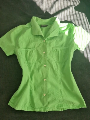 Grön Figursydd Skjorta - Vintage Peak Performance. Figursydd så sitter bra. Normal i storleken. Har några små fläckar på insidan av fickan som inte syns utanpå, se bild.