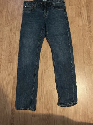 Mörkblå raka jeans från 157 - Säljer ett par mörkblå jeans från 157 med raka ben och klassisk femficksmodell. Jeansen har kontrastsömmar och metallknappar. Tillverkade i slitstark denim, perfekta för en avslappnad stil.