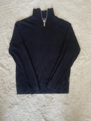 Svart halvzip tröja med från Jack and Jones - Klassisk svart tröja från jack an Jones med halv dragkedja och hög krage. Tröjan har långa ärmar och ribbade muddar vid ärmslut och nederkant. Perfekt för lager på lager och enkel att matcha med olika stilar.