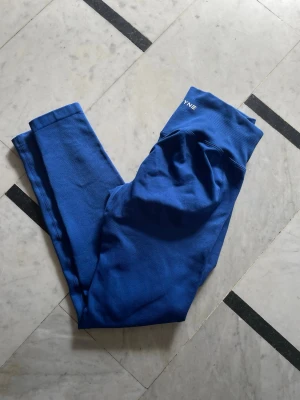 Blå seamless leggings från DFYNE - Snygga blå seamless leggings från DFYNE med hög midja och ribbad struktur upptill. Tillverkade i stretchigt funktionsmaterial som passar perfekt för träning eller chill. Logga i vitt framtill på linningen för en clean look.