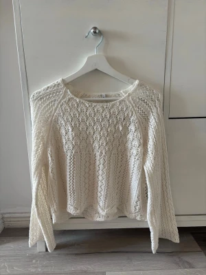 Vit stickad tröja från ONLY - Säljer en vit stickad tröja med snyggt hålmönster och rund hals. Tröjan har långa ärmar och är gjord i ett mjukt material som känns skönt mot huden. Perfekt för dig som gillar en stilren och trendig look. Aldrig använd💕