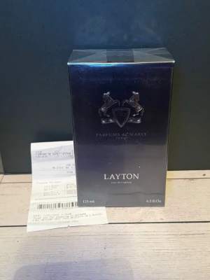 Parfums de Marly Layton 125 ml - Exklusiv parfym från Parfums de Marly, modellen Layton. Flaskan rymmer 125 ml och kommer i en elegant mörkblå förpackning med silverdetaljer och logotyp med två hästar. Eau de Parfum med lyxig känsla, tillverkad i Frankrike.