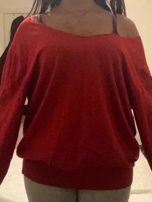 Röd off-the-shoulder tröja - Säljer en röd off-the- shoulder tröja med avslappnad passform och långa ärmar. Tröjan har bred mudd vid midjan och är tillverkad i ett mjukt tyg som känns skönt mot huden. Perfekt för dig som gillar en trendig och bekväm stil.