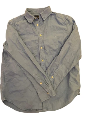 Blå skjorta från Ralph Lauren - Klassisk blå skjorta från Ralph Lauren med button-down krage och broderad logga på bröstet. Skjortan har långa ärmar och stängs med ljusa knappar framtill. Perfekt till jeans eller chinos för en clean och stilren look. Hör av er vid fler frågor eller funderingar, pris kan diskuteras.