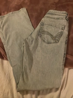 Ljusblå jeans med broderad ficka - Säljer ett par ljusblå jeans med snyggt broderi på bakfickan. Jeansen har klassisk femficksmodell och raka ben. Materialet är denim i bomull och färgen är tvättad ljusblå. Perfekta för en avslappnad och trendig look.