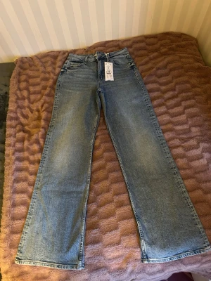 Comfy wide jeans i ljusblå denim Gina Tricot  - Säljer ett par comfy wide jeans från Perfect Jeans i ljusblå tvätt. Jeansen har hög midja, raka och vida ben samt klassiska fem fickor. Materialet är mjuk denim, perfekt för en avslappnad och trendig look.