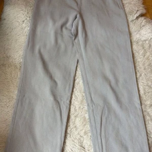 Armani Collezioni grå byxor storlek M - Säljer ett par ljusgrå manchesterbyxor med rak passform och klassisk midja. Byxor med fiskbensmönster. Byxorna har en rak passform och en dold dragkedja i sidan. Midjan är designad för en bekväm passform.Mått 80 cm, Innebensmått 75/99 cm. 