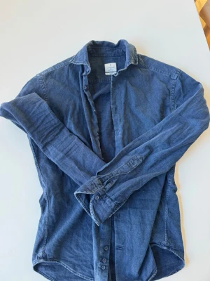 Blå skjorta från La Chemise  - Snygg blå skjorta från La Chemise Norrmalm i slim fit. Skjortan har klassisk krage, långa ärmar och knappar framtill. Tillverkad i mjuk bomull som känns skön mot huden. Skriv ifall du har några frågor!