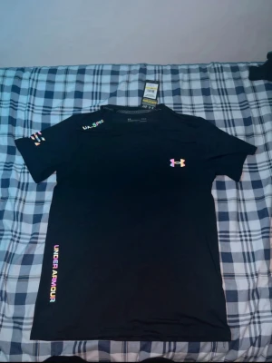 Svart träningströja från Under Armour - Pris går att diskuteras. Helt nya för stor för mig aldrig använt med prislapp. Snygg svart träningströja från Under Armour med korta ärmar och rund hals. Tillverkad i ett lätt och snabbtorkande funktionsmaterial, perfekt för intensiva träningspass. Diskret logga på bröstet och tryck på ärmen samt sidan.