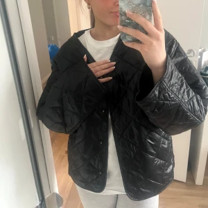 Svart quiltad jacka - Säljer en svart quiltad jacka med oversized passform. Jackan har knappar framtill så jackan går att ha knäppt också! Nypris 599kr! 
