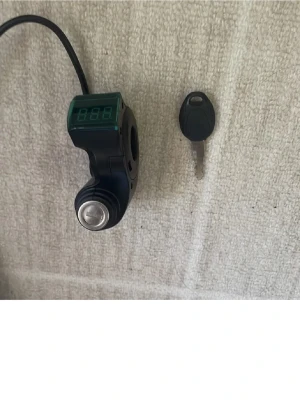 Elektroniskt tändningslås med display - Elektroniskt tändningslås med digital display och nyckel, perfekt för elcykel eller elscooter. Svart plastmaterial med inbyggd voltmätare och kablar för enkel installation. Passar styre med rund form och har en metallnyckel med svart plasthandtag.