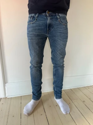 Replay jeans - Säljer ett par blå slim fit jeans med snygg tvätt och klassiska fem fickor. Jeansen har normal midja, smal passform och är tillverkade i stretchigt denimtyg för extra komfort. Perfekta till vardagslooken och lätta att matcha med olika stilar. Storlek 30W/30L