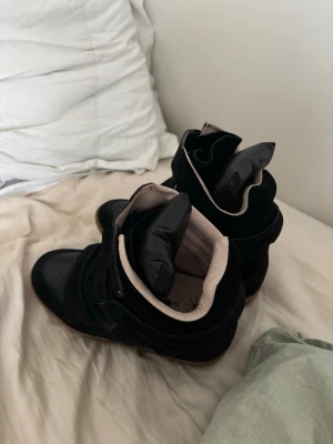 Svarta höga sneakers med kardborre - Snygga svarta sneakers med högt skaft och flera kardborreband. Skorna har en cool design med vadderad plös och kontrastfärgad insida i beige. Materialet är en mix av mocka och läderimitation. Perfekta för dig som gillar streetstyle och vill sticka ut. ‼️‼️en av inner sulorna är lite skrapade efter jag försökte lägga in sko skydd‼️‼️