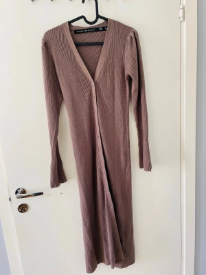 Ribbad långklänning/ kofta - Lång ribbad klänning i beige som även fungerar som en längre kofta. Knappar finns att knäppa hela vägen ned till.