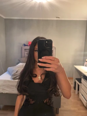 Svart långklänning med spets - Säljer en elegant svart långklänning med spetsdetaljer i midjan och omlottdrapering upptill. Klänningen är ärmlös och har en figurnära passform som framhäver siluetten. Perfekt för speciella tillfällen och kvällar.