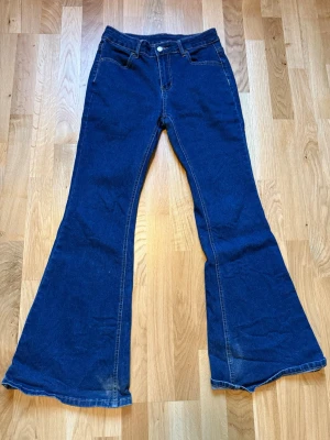 Mörkblå bootcut jeans - Säljer ett par mörkblå bootcut jeans i storlek L med sitter som storlek M Jeansen har mellan midja. Det är ett bra material och är väldigt utsvängda längst ner vid byxbenet. Har använt typ 1-2 gånger.