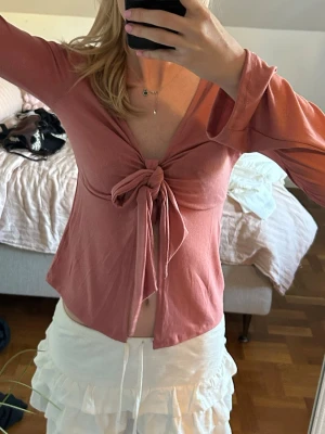 Rosa långärmad topp med knyt - Rosa långärmad topp med djup v-ringning och stor knytning framtill. 