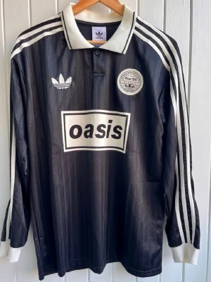 Oasis - Långärmad fotbollströja - Säljer en svart långärmad Oasis-supportertröja för bandets turné under 2025. Tröjan är en reprint i nyskick. Aldrig använd. ”25” på ryggen.      Storlek: Medium