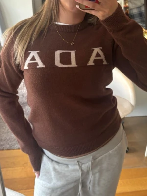 Brun stickad tröja med ADA-tryck - Säljer en brun stickad tröja med  rund halsringning, långa ärmar och ribbade muddar vid ärmslut och nederkant. Supermysig o stretchig☺️