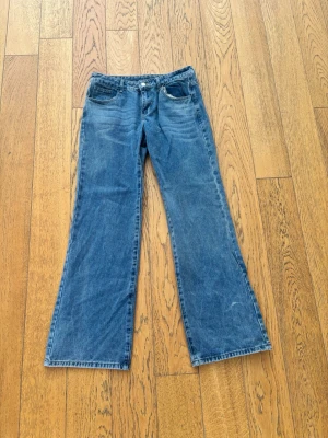 Blå lågmidjade jeans med utsvängda ben - Snygga blå  jeans med klassisk femficksdesign och utsvängda ben. Jeansen har låg midja och är tillverkade i denim med lätt tvättad look. Perfekta för en avslappnad och trendig stil.