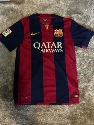 Barcelona matchtröja Nike röd/blå - Säljer en FC Barcelona matchtröja från nike. 2014-2015 tröjan som är eftertraktad. Tröjan är i dri-fit och är äkta vilket gör den exklusive. I väldigt fint skick för utom en väldigt liten prick på höger arm som knappt syns. Priset är inte huggt i sten, hör av er vid funderingar😁
