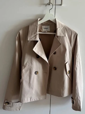 Kort beige trenchcoat från ONLY - Söt somrig jacka ifrån only, helt oanvänd då jag ångrade mig och inte tycker den passar mig.🌸 storlek xs . Inga fler bilder. 