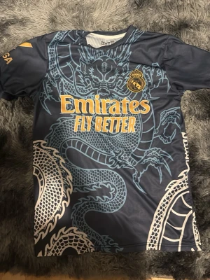 Real Madrid tröja  - Real Madrid tröja som är marinblå me lite guldfärg i den och har använder den några par gånger, det passar som ett S