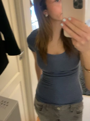 Blå tight topp med kort ärm - Snygg blå topp med tight passform och korta ärmar. T-shirten har rund halsringning och är enkel att matcha till olika outfits. Perfekt för dig som gillar en stilren och enkel look.