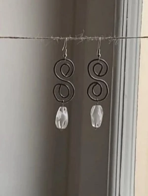 Silvriga örhängen med pärldetalj - Unika örhängen i silvrig metall med spiralformad design och en transparent pärlliknande detalj längst ner. Perfekta för dig som gillar statement-accessoarer med en konstnärlig touch. Mina handgjorda örhängen.  Vita pärlor på silverfärgad metalltråd.  Nickelfria!  Följ min Instagram för mer <3 @veras.smycken
